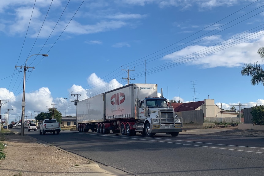 Un camion sur la route avec un ciel bleu en arrière-plan.