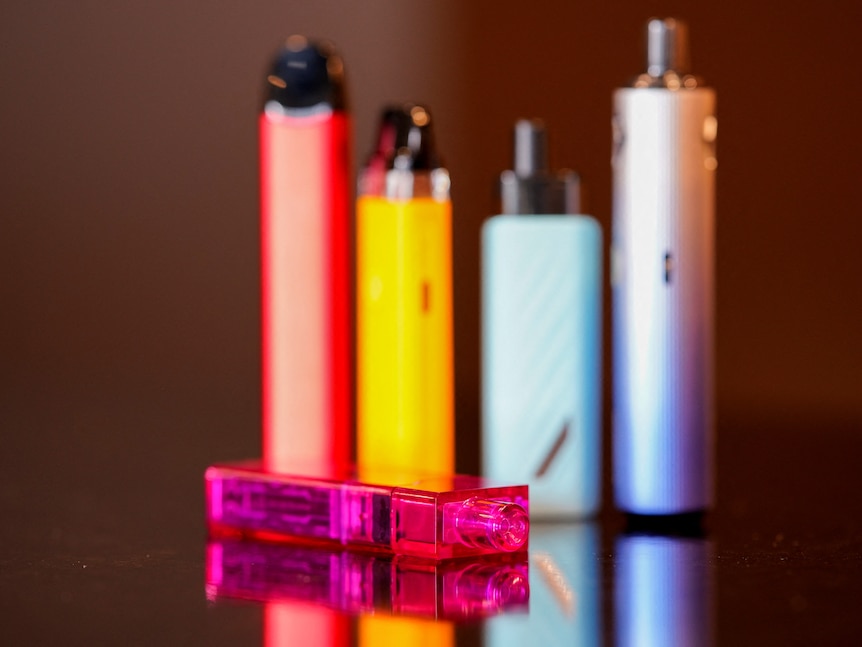 five colourful vapes standing on a black-coloured counter