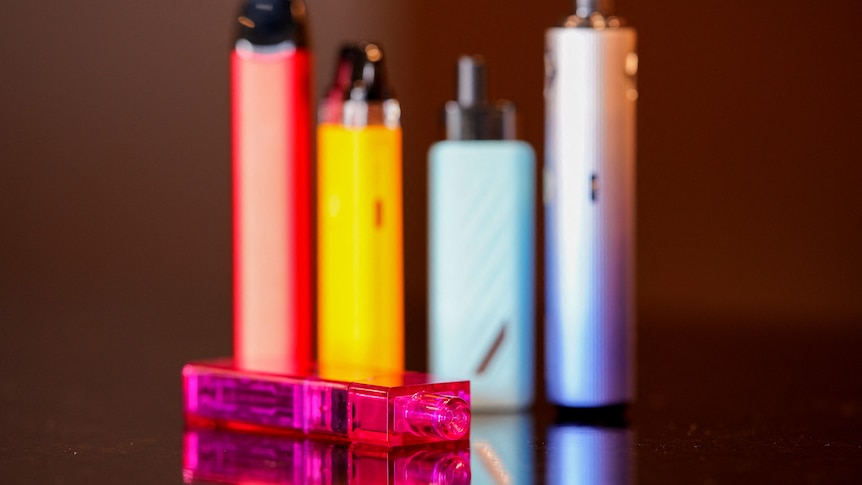 five colourful vapes standing on a black-coloured counter