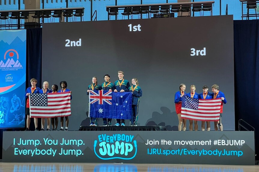 a podium of competitors holding their country flags.
