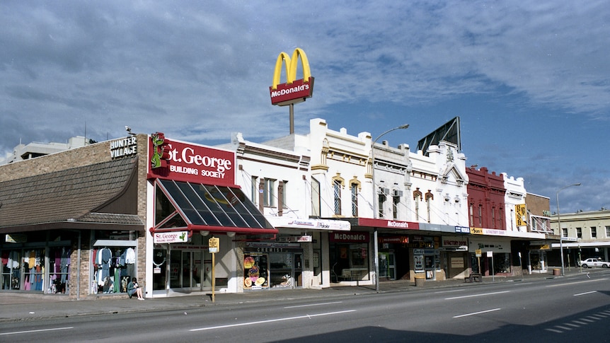 An archival image of a street in Newcastle in 1986. A collection of shops including a McDonalds store and a bank.
