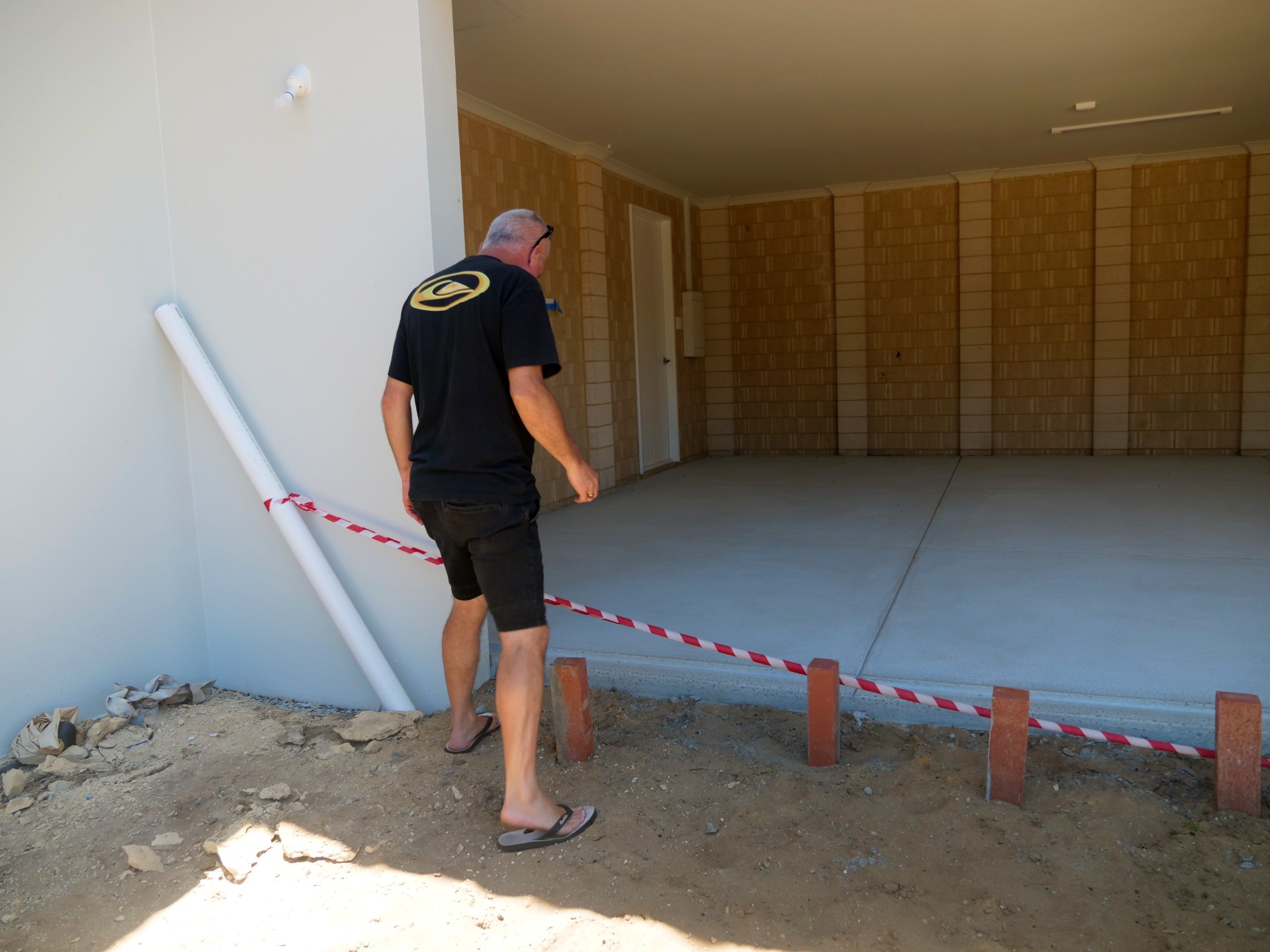 Un hombre se encuentra junto a su casa incompleta.