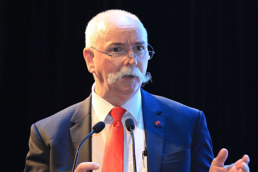 A man talking at a podium in a suit.