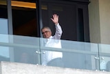 Dominic Dwyer of the World Health Organization team waves at journalists from a hotel room balcony.