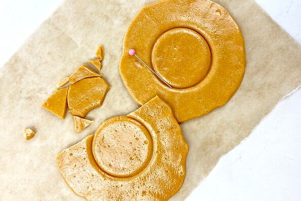 Some cracked yellow honeycomb biscuits on parchment paper