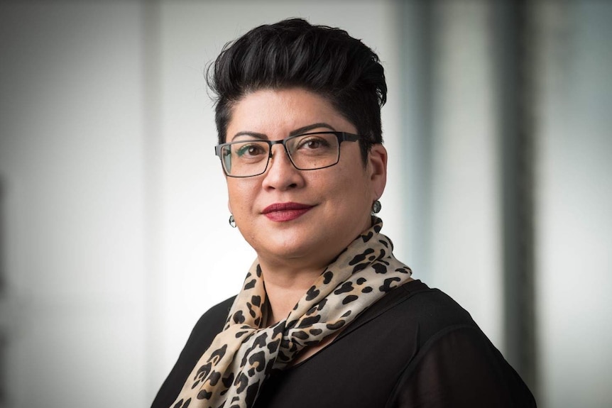 Wendy Robertson wearing a scarf and glasses looks straight at the camera.