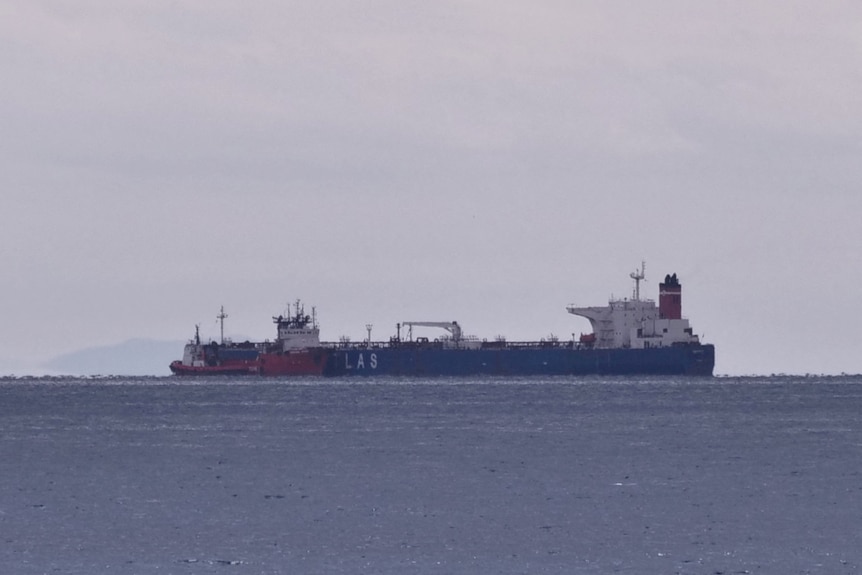 An oil tanker is seen anchored in flat, calm water.