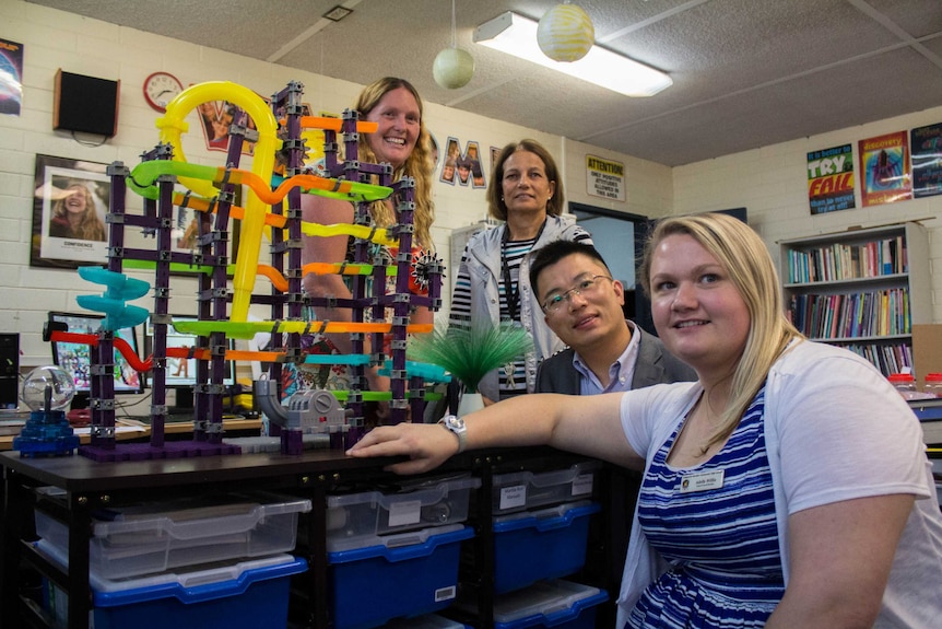 Image of several teachers posing next to a rube goldberg device in a classroom at Kalgoorlie-Boulder Community High School.