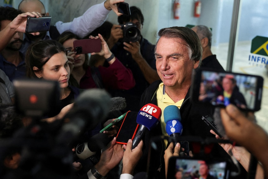 Brazil's former President Jair Bolsonaro speaks with media as he arrives at the airport 
