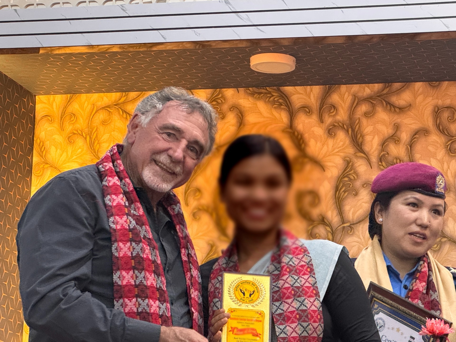 Um homem e duas mulheres juntos, uma delas segurando um troféu, com os rostos desfocados