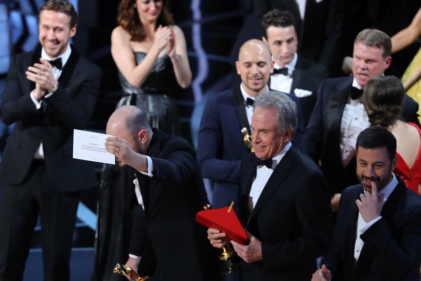 Jordon Horowitz holds up the card for Best Picture next to Warren Beatty and Jimmy Kimmel.