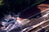 A taxi drives through a large body of water on a road