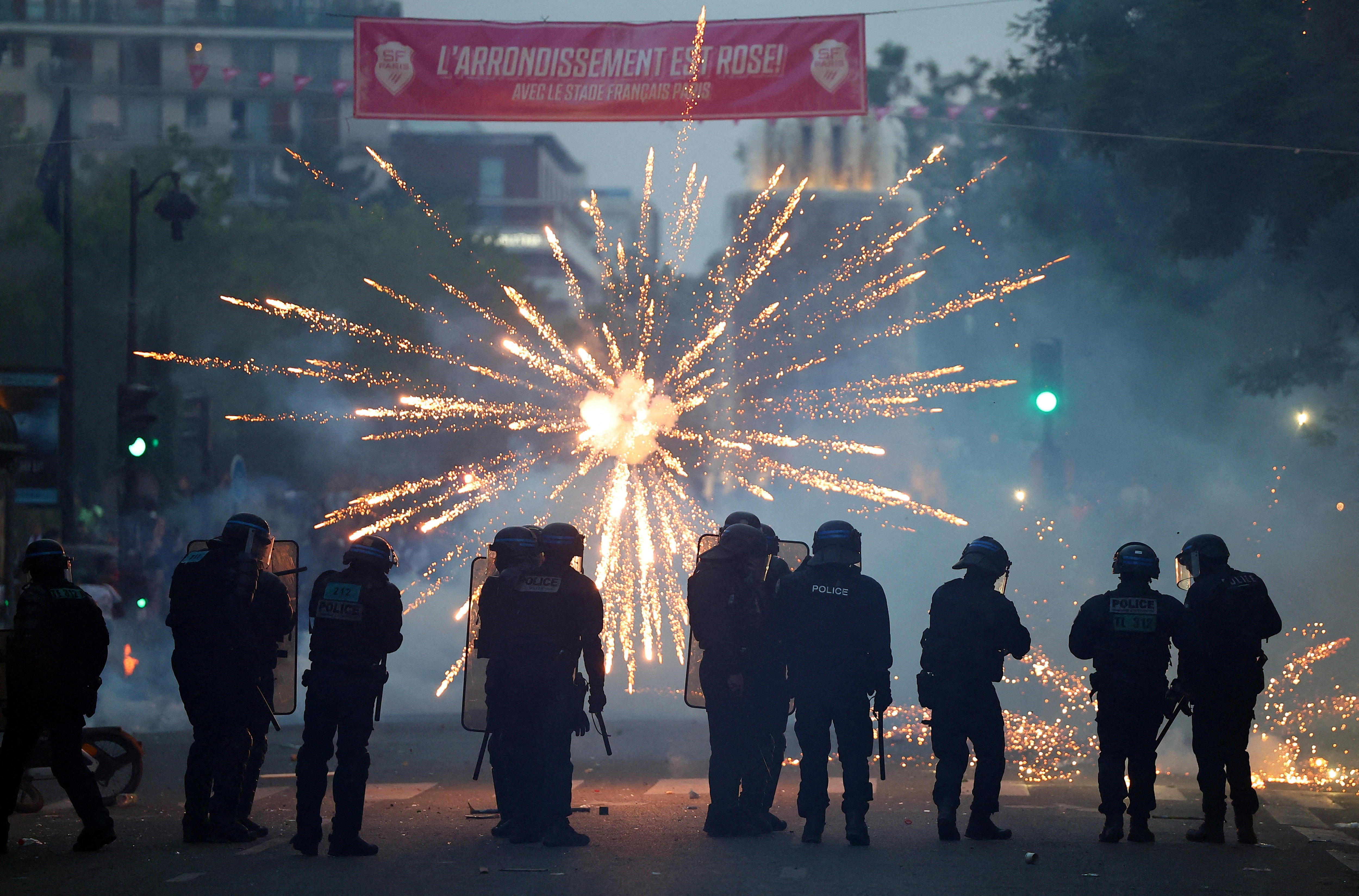 Police are silhouetted as a firework explodes on a Paris street.