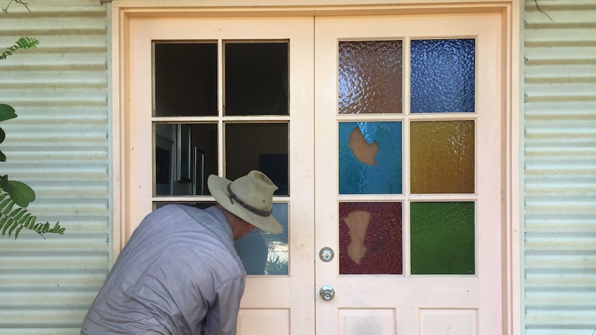 A trademan repairing a set of front doors with stained glass panels which have been smashed in