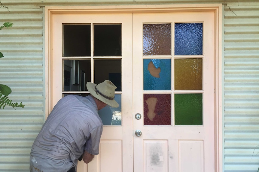 A trademan repairing a set of front doors with stained glass panels which have been smashed in