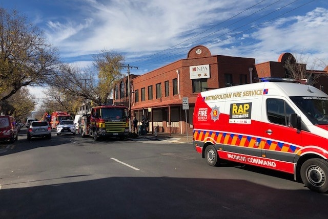 Fire vehicles parked on the road outside of a brick building