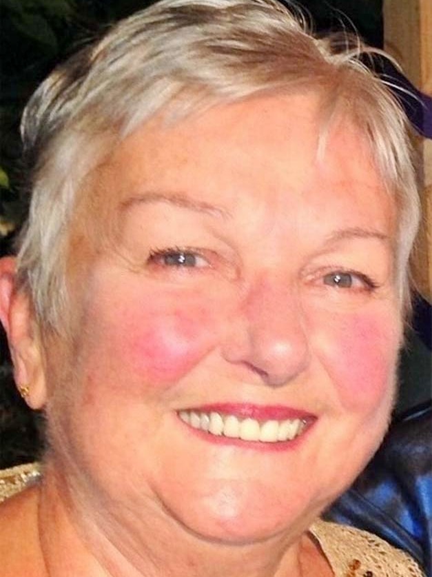 Lady smiling at camera with pink lipstick and a short grey pixie cut