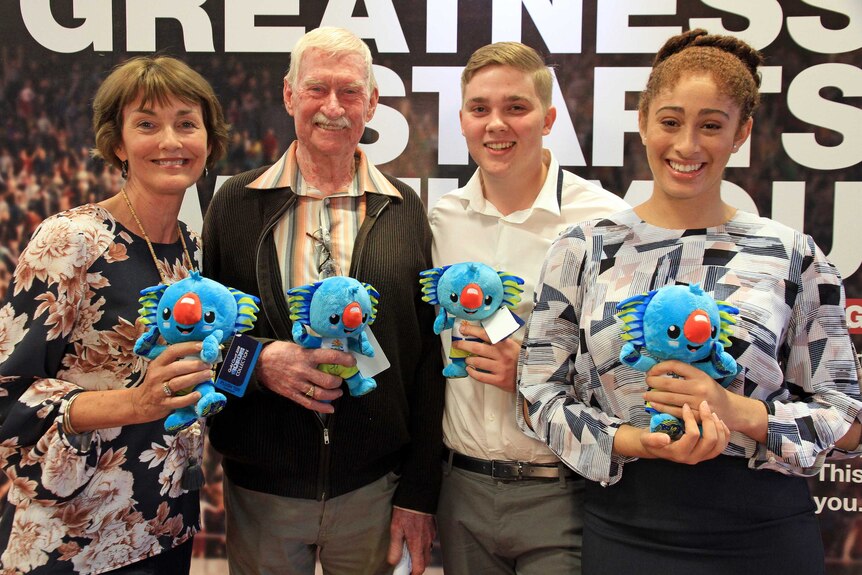 Two men and two women volunteers standing with Commonwealth Games Mascot toy Boribi