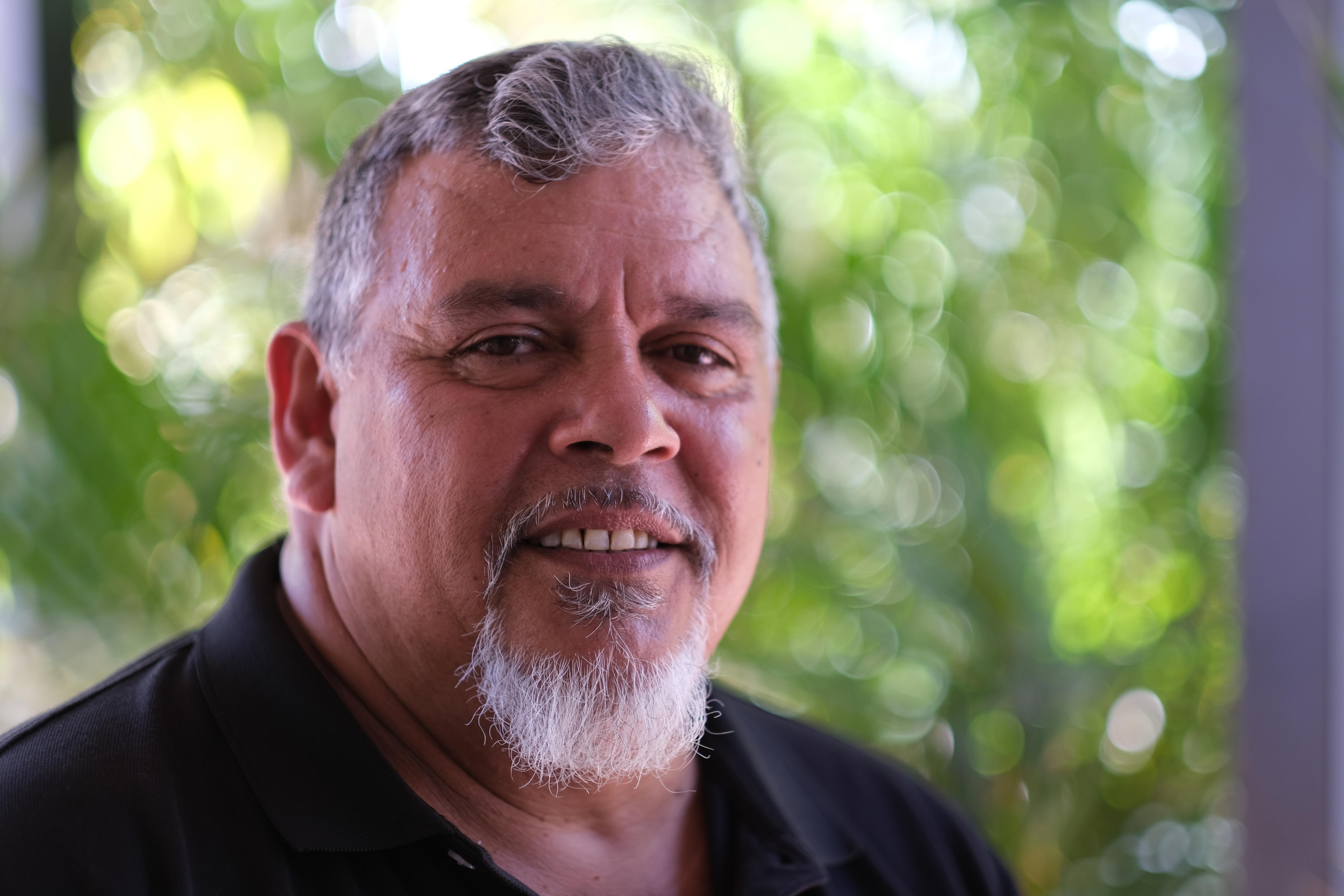 Un hombre sonriente con un fondo verde. 