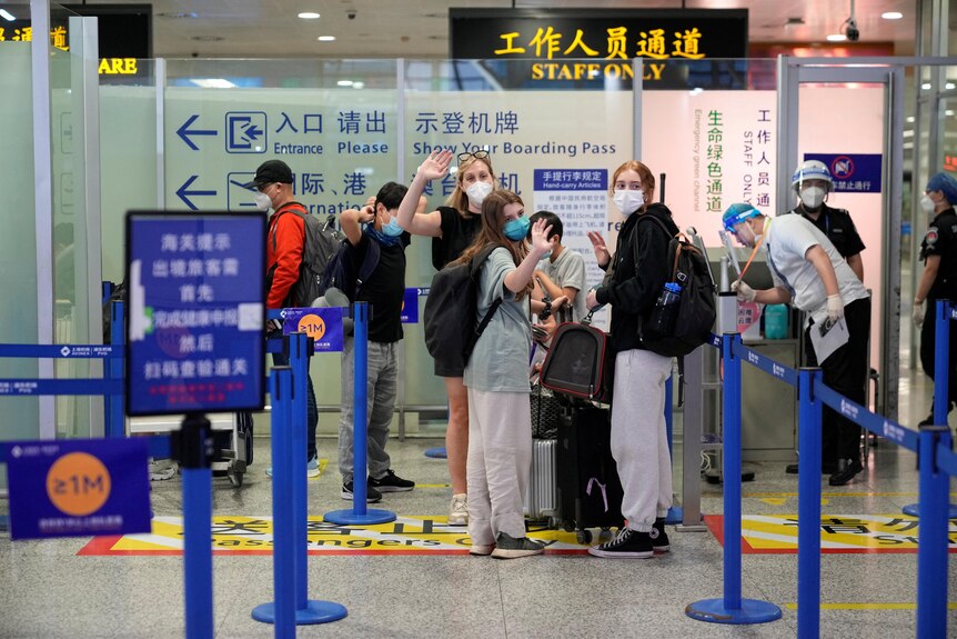 The three women are clustered around their suitcases as they enter customs at the international airport