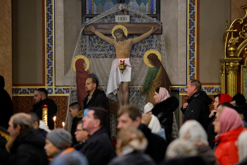 People in a church in Donetsk stand near an image of Christ being crucified