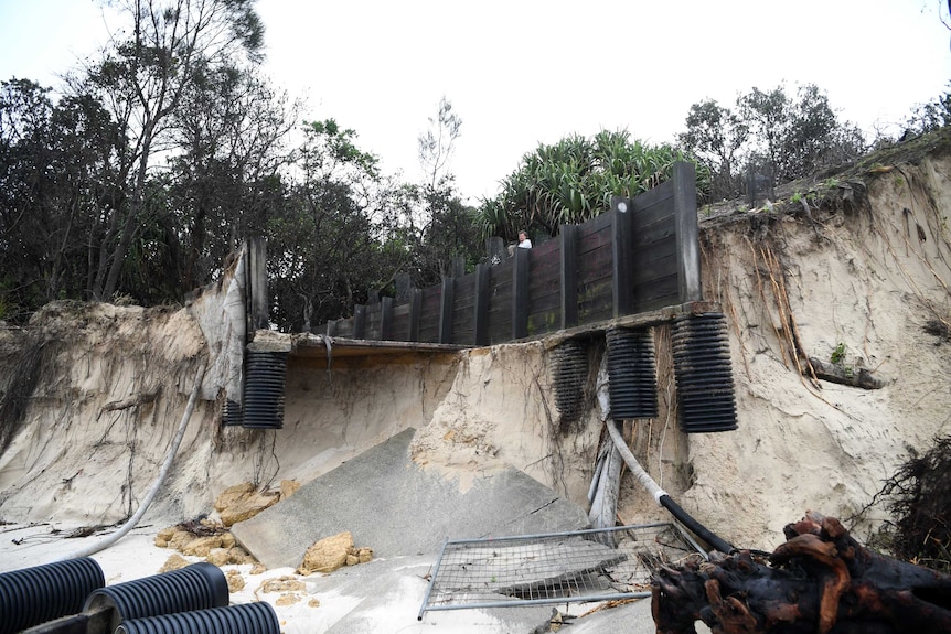 A disabled access wooden bridge is damaged on a sand hill at a beach
