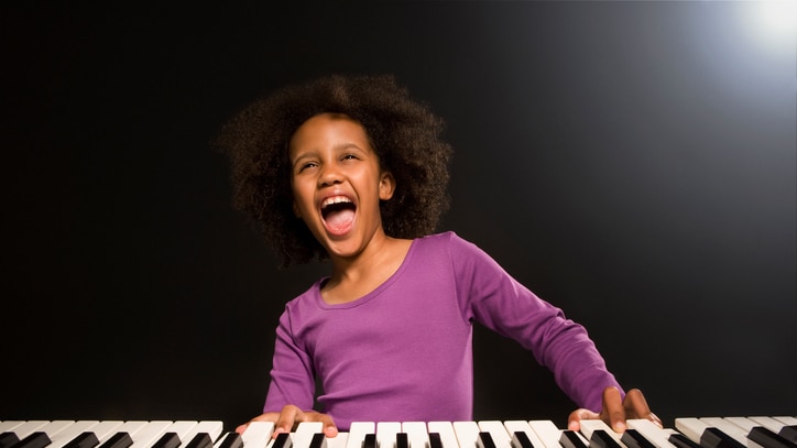 A young girl singing while playing piano