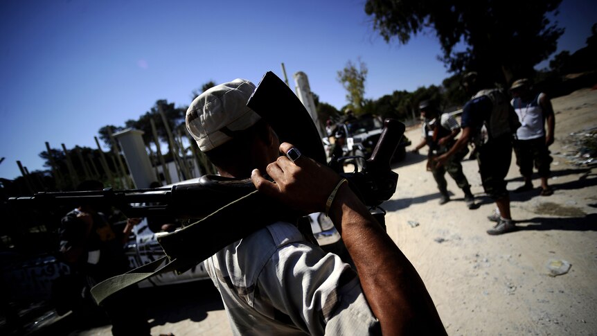 Libyan rebels gather at the entrance of the al-Maser forest in southern Tripoli where they found boxes of ammunition hidden