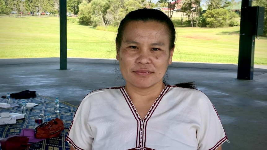 a woman with black hair in a white embroidered top