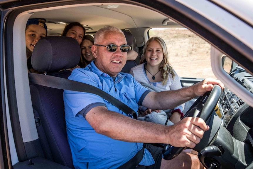 Family smiles from the cabin of a car