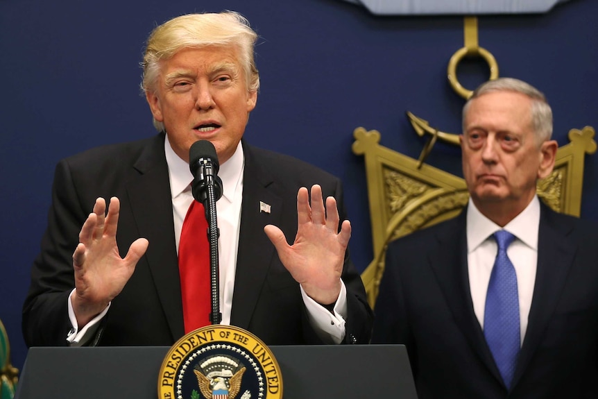 Defence Secretary James Mattis watches as Donald Trump speaks to the media.