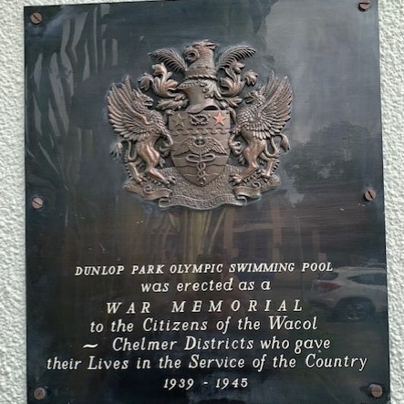 A war memorial plaque on the wall at the entrance to Dunlop Park Memorial Swimming Pool