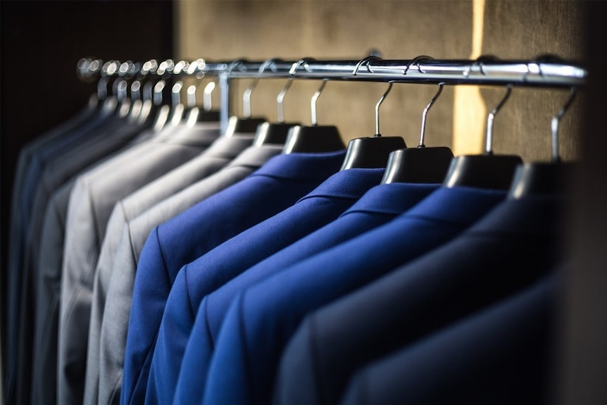 A rack of suits in different shades of blue