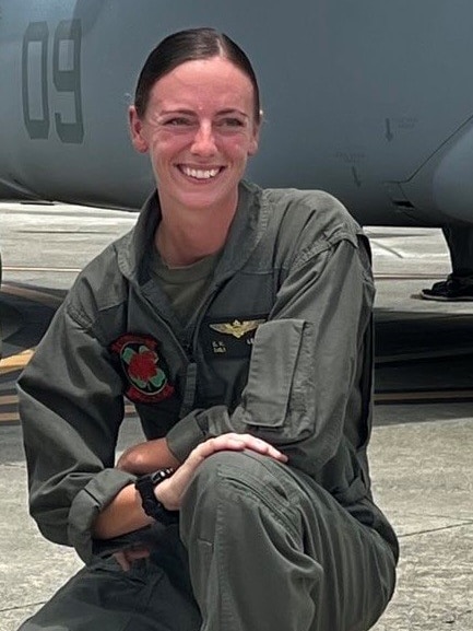 Captain Eleanor V. LeBeau crouches in uniform in front of an aircraft