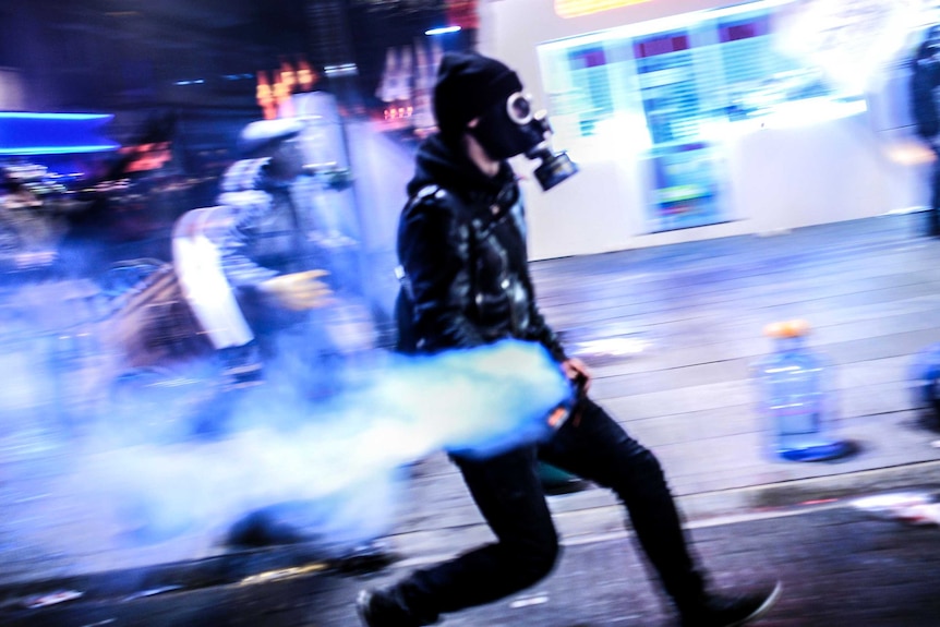 A protester wearing a gas mask runs with a gas canister during clashes with police in Kadikoy.