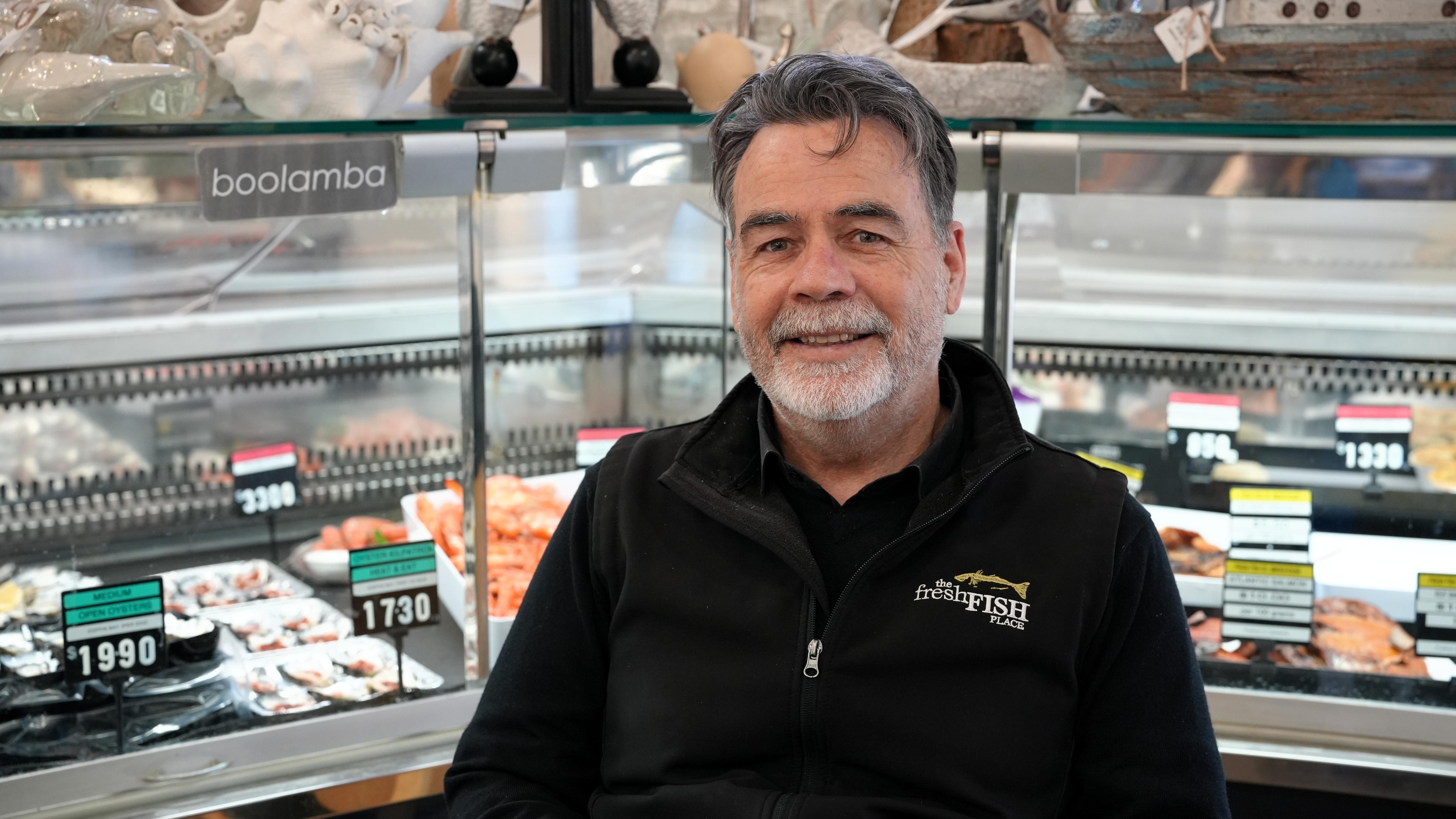 golf a man in black jacket sits in front of fish counter