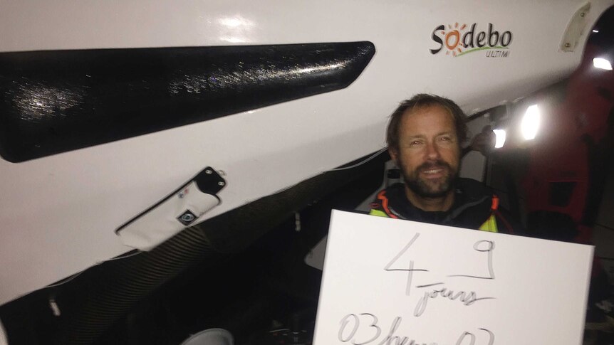 French skipper Thomas Coville poses for a photo with a placard which reads "49 days 3 hours and 38 seconds" as he sails in the round-the-world solo sailing race.