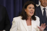 Jane Hume in a white suit at a press conference. 