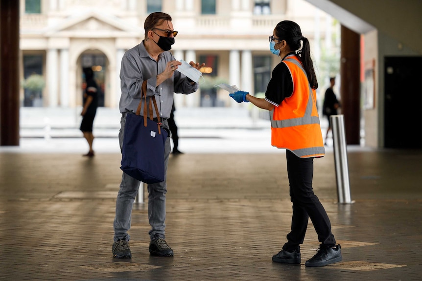 Passenger handed mask by staff at train station