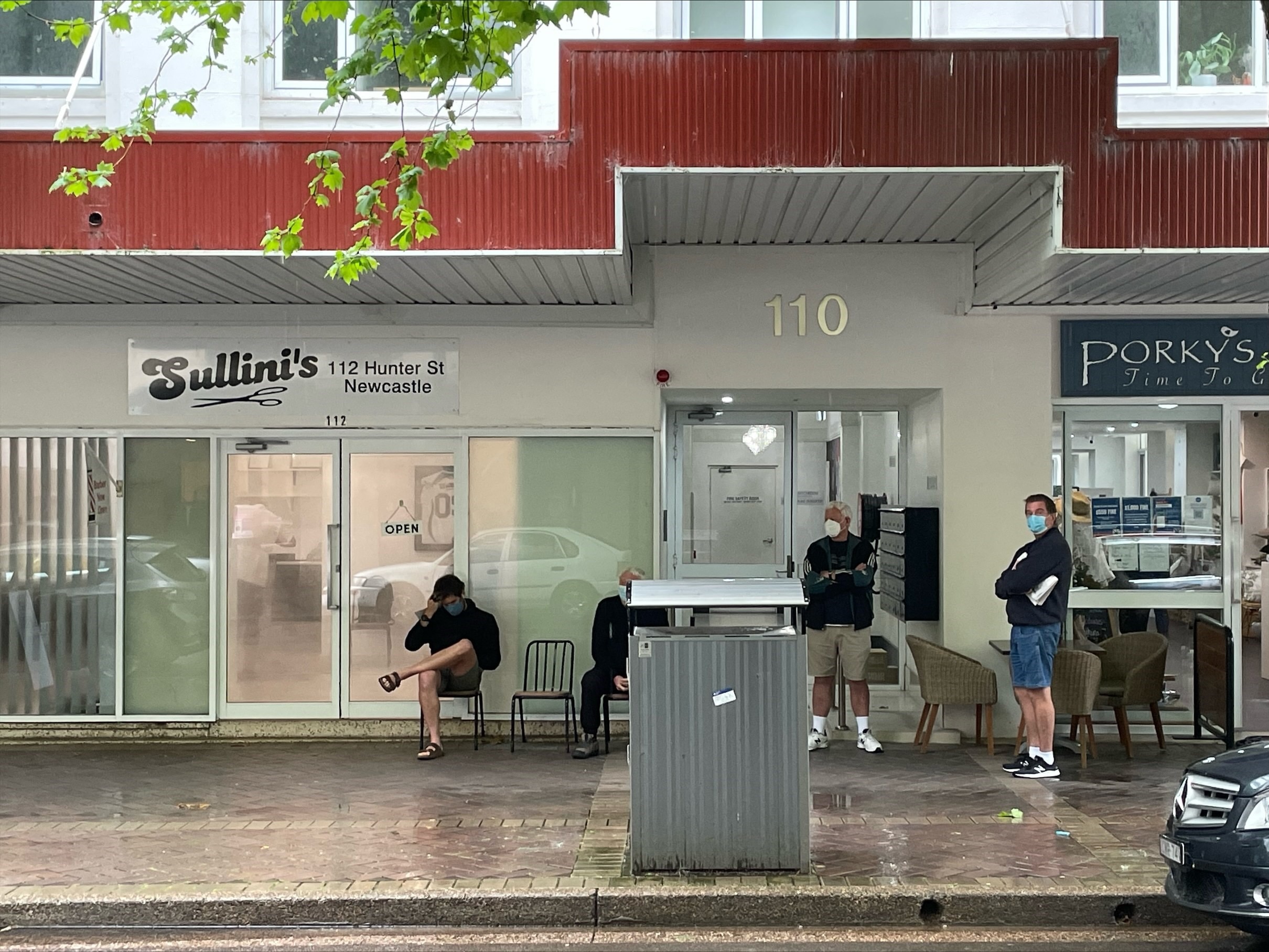 Men lining outside a barbershop in Newcastle.