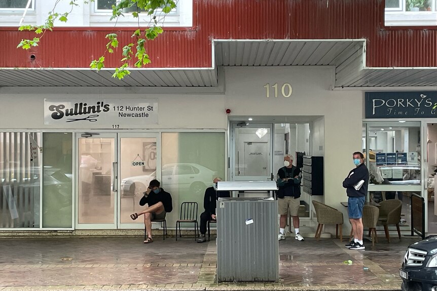 Men lining outside a barbershop in Newcastle.