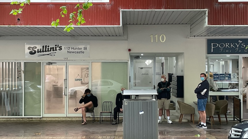 Men lining outside a barbershop in Newcastle.