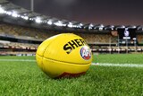 A yellow AFL ball sits on the boundary ahead of a night game at the Gabba.