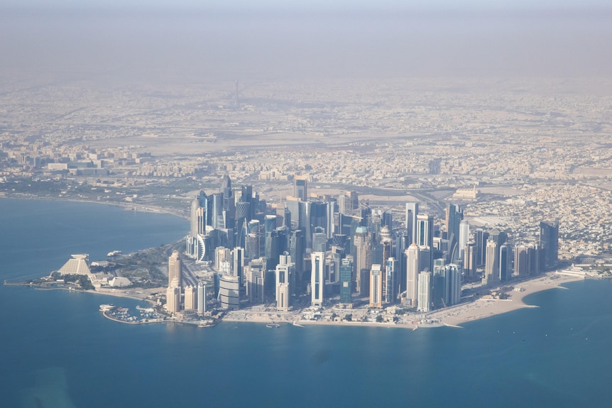 The city of Doha rises from the desert of Qatar, seen from above via an airplane