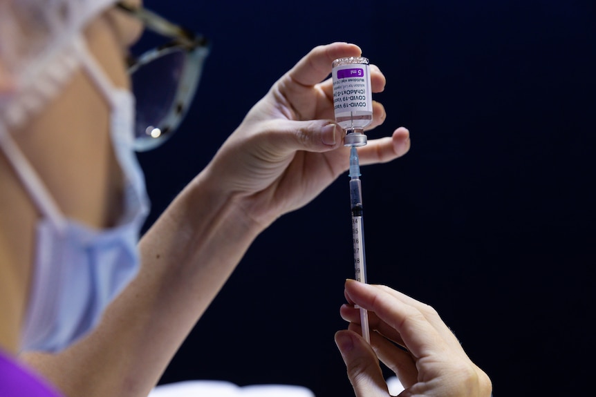 a nurse fills a syringe with covid-19 vaccination fluid