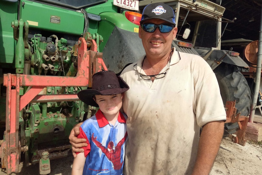 Tony Jeppeson and young son Sam standing in front of their tractors