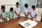 Some of the rescued soccer team members bowing their heads respectfully in front of a sketch of the Thai Navy SEAL diver