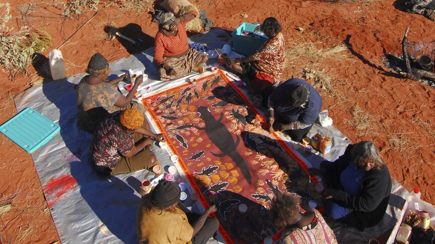 Aboriginal women from Warakurna collaborating on a painting associated with the Lungarta (Blue Tongue lizard) Dreaming.