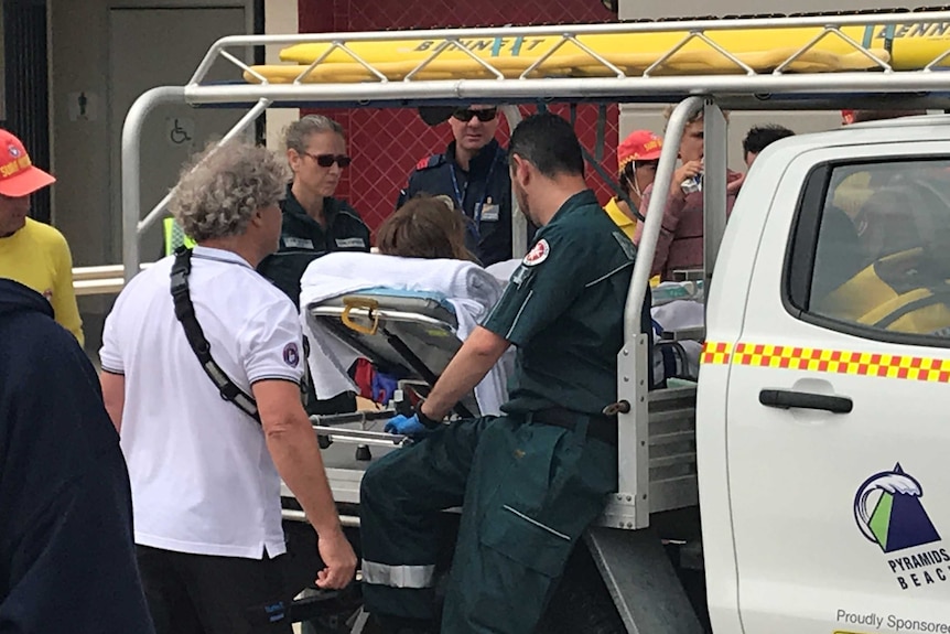 A young man lies on a stretcher in the back of an emergency services vehicle.