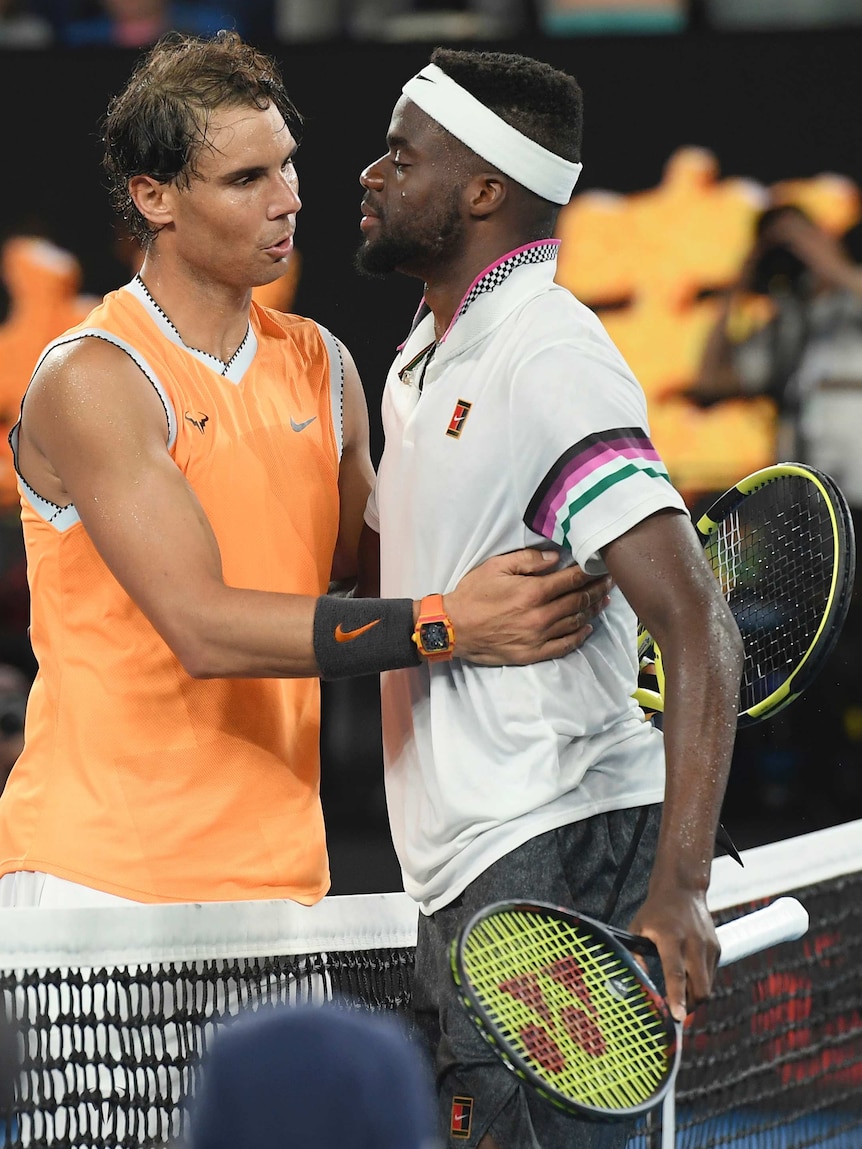 Rafael Nadal and Francis Tiafoe hug at the net.
